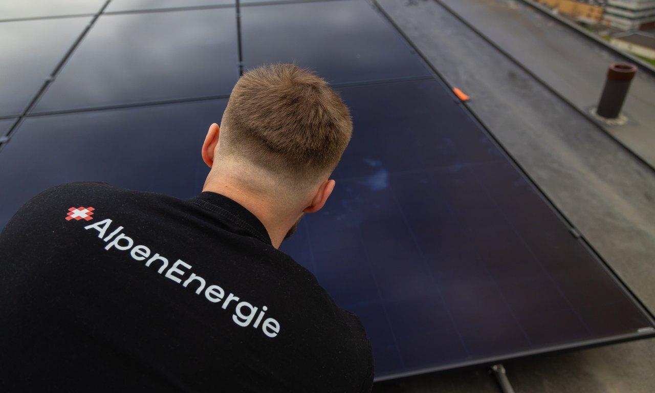 AlpenEnergie-Mitarbeiter prüft ein Solarmodul auf einem Dach