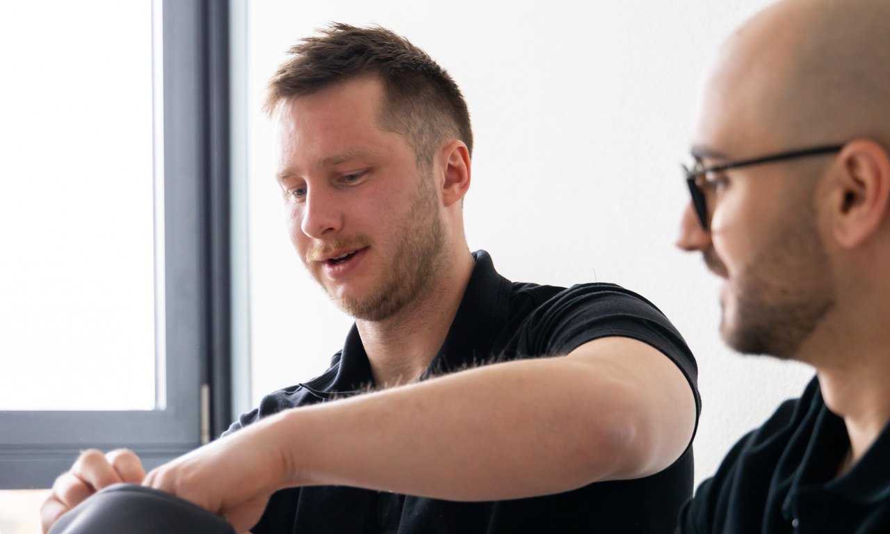 Zwei AlpenEnergie-Mitarbeiter besprechen Unterlagen an einem Tisch